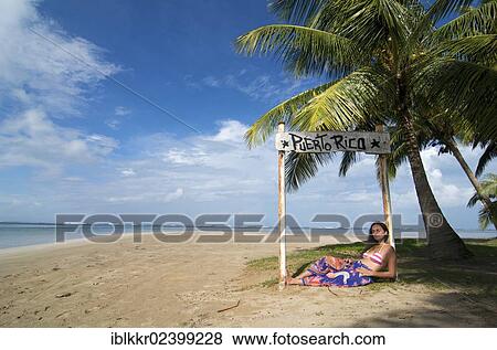 Stock Photo - "Tourist lying under a sign with the words Puerto Rico, Luquillo Beach, Puerto Rico, Caribbean, North America". Fotosearch