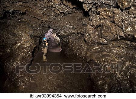 Picture - "Tourist standing in a subterranean lava tube created by an eruption of the Piton de la Fournaise volcano, Le Grand Brule, La Reunionhiker". Fotosearch