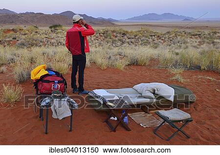 "Tourist standing in an open air campsite at Schafberg Camp on Tok Tokkie Trail, Namib Rand Nature Reserve, Namib Desert, Namibia, Africa" View Large Photo Image Stock Image - "Tourist standing in an open air campsite at Schafberg Camp on Tok Tokkie Trail, Namib Rand Nature Reserve, Namib Desert, Namibia, Africa". Fotosearch
