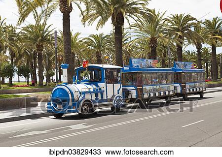 Stock Image - "Tourist train in front of palm trees, Salou, Catalonia, Spain, Europe". Fotosearch