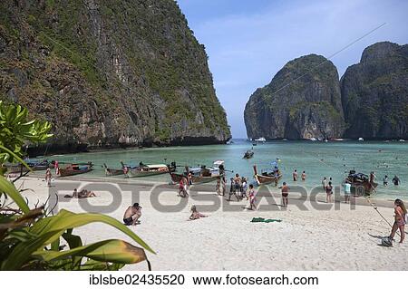 Stock Image - "Tourists and longtail boats on the sandy beach of Maya Beach, Ko Phi Phi Island, Phuket, Thailand, Asia". Fotosearch