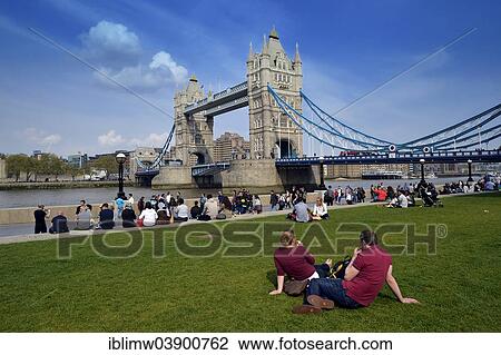 Stock Image - "Tourists relaxing in Potters Fields Park in front of Tower Bridge, London, England, United Kingdom, Europe". Fotosearch