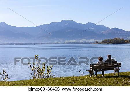 "Tourists sitting on a bench at Lake Chiemsee, Island Frauenchiemsee or Fraueninsel, Chiemsee, Upper Bavaria, Bavaria, Germany, Europe" View Large Photo Image Stock Image - "Tourists sitting on a bench at Lake Chiemsee, Island Frauenchiemsee or Fraueninsel, Chiemsee, Upper Bavaria, Bavaria, Germany, Europe". Fotosearch