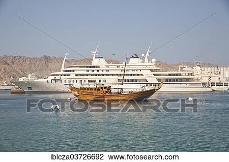 Stock Image - "Traditional dhow in front of modern luxury yacht belonging to the Sultan, Muscat, Oman, Asia". Fotosearch