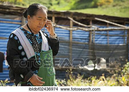 Picture - "Traditionally dressed woman from the mountain or hill tribe people, of the Hmong ethnic minority from East Asia, talking on a mobile phone, Thung Dok Bua Tong, Amphoe Khun Yuam, Mae Hong Son Province, northern Thailand, Thailand, Asia". Fotosearch