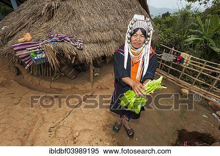 Stock Photography - "Traditionally dressed woman from the Akha people, hill tribe, ethnic minority, standing outside a straw hut with washed vegetables, Chiang Rai Province, Northern Thailand, Thailand, Asia". Fotosearch