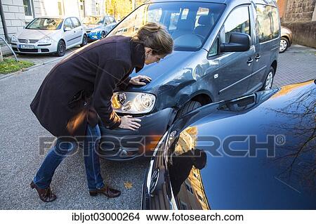 Picture - "Traffic accident, woman observing the slight body damage to a car, crash while turning from an exit, Germany, Europe". Fotosearch