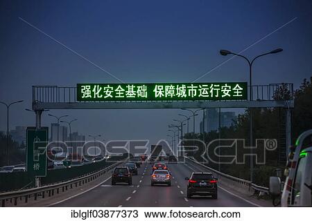 Stock Image - "Traffic on a motorway at dusk, illuminated with a Chinese banner, Beijing, China, Asia". Fotosearch