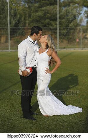 "Trash the dress, bride and groom kissing on a rugby pitch" View Large Photo Image Picture - "Trash the dress, bride and groom kissing on a rugby pitch". Fotosearch