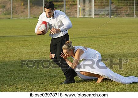Stock Photo - "Trash the dress, bride and groom playing rugby, bride tackling the groom". Fotosearch