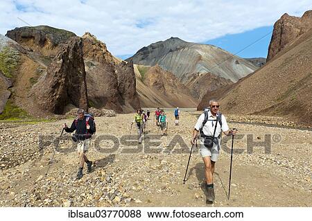 Stock Photo - "Trekking, group of hikers crossing a stony creek bed, Litla Brandsgil torrential stream, rhyolite rocks, Blahnjukur volcano at the back, Landmannalaugar, Rangarping ytra, Suourland, Iceland, Scandinavia, Europe". Fotosearch