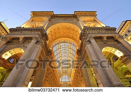 Stock Image - "Triumphal Arch to the Cathedral Square, entrance to the luxury shopping arcade, roofed gallery of Galleria Vittorio Emanuele II, twilight shot at the blue hour, Milan, Lombardy, Italy, Europe". Fotosearch