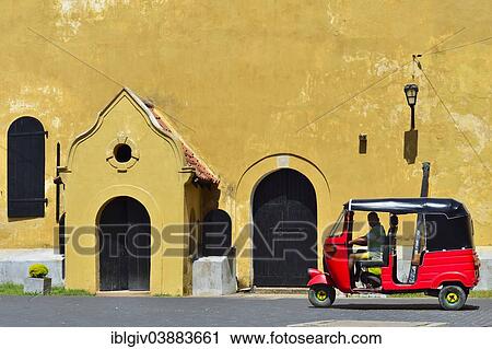 Stock Image - "Tuk-tuk in front of the Warehouse Building in Queens Street, Galle Fort, Galle, Southern Province, Sri Lanka, Asia". Fotosearch
