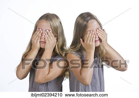 Stock Image - "Twin girls, 9, holding their eyes closed". Fotosearch