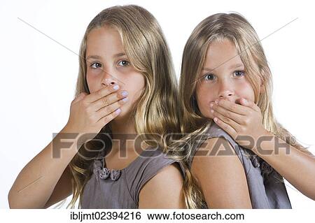 Stock Photograph - "Twin girls, 9, holding their mouths closed". Fotosearch