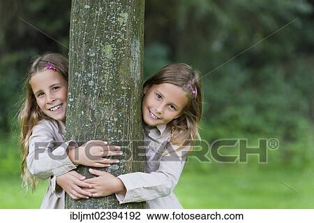 "Twin girls, 9, looking from the left and the right behind a tree" View Large Photo Image Stock Image - "Twin girls, 9, looking from the left and the right behind a tree". Fotosearch