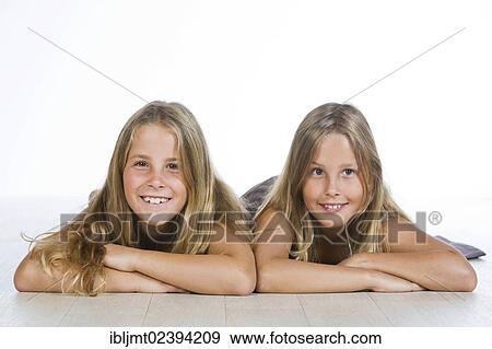 "Twin girls, 9, lying on their bellies and smiling" View Large Photo Image Stock Photo - "Twin girls, 9, lying on their bellies and smiling". Fotosearch