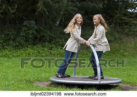 "Twin girls, 9, turning on a carousel on a playground" View Large Photo Image Stock Photo - "Twin girls, 9, turning on a carousel on a playground". Fotosearch
