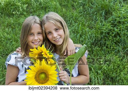 Stock Photo - "Twin girls, 9, with sunflowers". Fotosearch