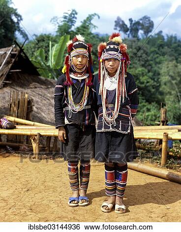 Stock Photograph - "Two Akha girls in a mountain village in traditional costume and headdress, Chiang Rai Province, Northern Thailand, Thailand, Asia". Fotosearch