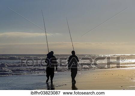 Stock Photo - "Two anglers walking with their fishing rods along the seaside beach, Maspalomas, Gran Canaria, Canary Islands, Spain, Europe". Fotosearch