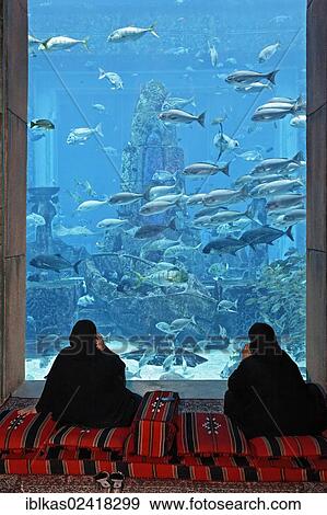 Two Arab women talking on their cell phones in front of an aquarium in The Lost Chambers, a theme park based on the legend of Atlantis, Atlantis Hotel, The Palm Jumeirah, Dubai, United Arab Emirates, Middle East, Asia View Large Photo Image Stock Photo - Two Arab women talking on their cell phones in front of an aquarium in The Lost Chambers, a theme park based on the legend of Atlantis, Atlantis Hotel, The Palm Jumeirah, Dubai, United Arab Emirates, Middle East, Asia. Fotosearch