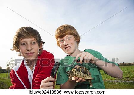 Stock Photograph - Two boys examining a turtle with a magnifying glass. Fotosearch