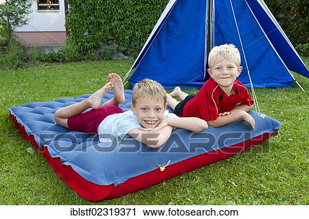 Two boys lying on an air mattress while camping in the garden View Large Photo Image Stock Image - Two boys lying on an air mattress while camping in the garden. Fotosearch