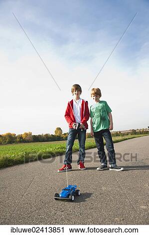 Stock Image - Two boys playing with a remote-controlled model car. Fotosearch