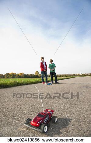 Two boys playing with a remote-controlled model car View Large Photo Image Stock Photograph - Two boys playing with a remote-controlled model car. Fotosearch