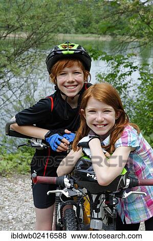 Stock Photo - Two children, boy and girl, with mountain bikes and helmets. Fotosearch