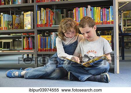 Stock Photography - "Two children reading reading a book in a public library, Coswig, Saxony, Germany, Europe". Fotosearch