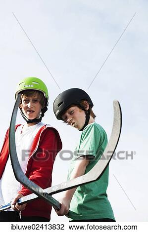 Stock Image - Two cool boys playing roller hockey with hockey sticks. Fotosearch