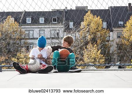 Two cool boys sitting with a basketball on a playground View Large Photo Image Stock Image - Two cool boys sitting with a basketball on a playground. Fotosearch