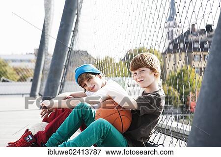 Stock Photo - Two cool boys sitting with a basketball on a playground. Fotosearch