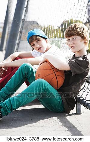 Two cool boys sitting with a basketball on a playground View Large Photo Image Stock Photo - Two cool boys sitting with a basketball on a playground. Fotosearch