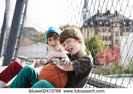 Two cool boys sitting with a basketball on a playground View Large Photo Image Stock Photo - Two cool boys sitting with a basketball on a playground. Fotosearch