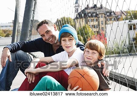 Stock Photo - Two cool boys sitting with their father on a playground. Fotosearch