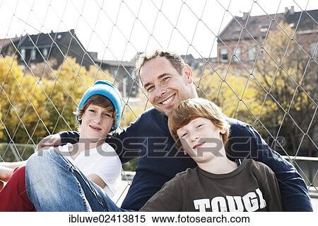 Two cool boys sitting with their father on a playground View Large Photo Image Stock Photography - Two cool boys sitting with their father on a playground. Fotosearch