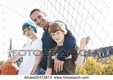 Two cool boys standing with their father on a playground View Large Photo Image Stock Image - Two cool boys standing with their father on a playground. Fotosearch