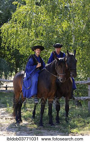Stock Image - "Two Csikos on horseback, Tanyacsarda Stud, Kecskemet, Puszta, Hungary, Europe". Fotosearch