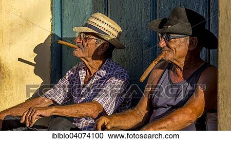 "Two elderly Cubans sitting on a doorstep in the evening light, smoking cigars, Trinidad, Sancti Spiritus Province, Cuba, North America" View Large Photo Image Stock Image - "Two elderly Cubans sitting on a doorstep in the evening light, smoking cigars, Trinidad, Sancti Spiritus Province, Cuba, North America". Fotosearch