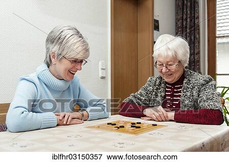 "Two elderly women, senior citizens, mother and daughter, playing the board game """"Nine Men's Morris"""", Rehna, Mecklenburg-Western Pomerania, Germany, Europe" View Large Photo Image Stock Photo - "Two elderly women, senior citizens, mother and daughter, playing the board game """"Nine Men's Morris"""", Rehna, Mecklenburg-Western Pomerania, Germany, Europe". Fotosearch