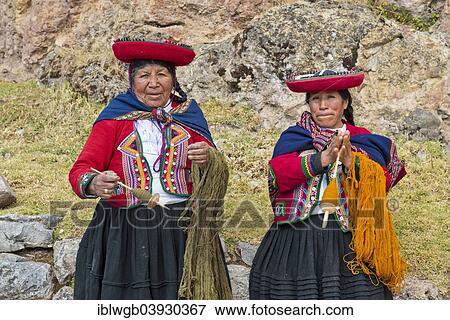 Stock Photo - "Two elderly women wearing hats, Quechua Indians, in traditional dress, spinning wool with wooden spindles, Cinchero, Urubamba Valley, Peru, South America". Fotosearch