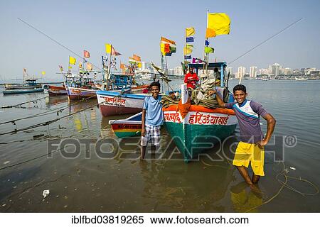 Stock Photography - "Two fishermen and some fishing boats in front of the skyline of the suburb Churchgate seen across the Back Bay, Mumbai, Maharashtra, India, Asia". Fotosearch