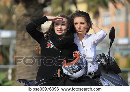 Stock Photograph - "Two girlfriends, teenagers, with a scooter, Menton, Alpes-Maritimes, Provence-Alpes-Cote d'Azur, France, Europe". Fotosearch
