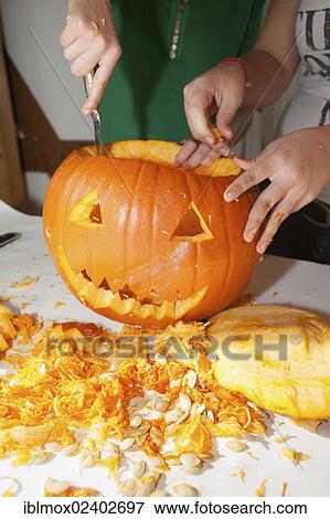 Stock Photo - "Two girls, about 14 years, carving a face into a Halloween pumpkin". Fotosearch