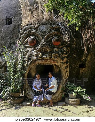 Stock Image - "Two girls in the mouth of a spirit at the entrance to Xieng Khuan Buddha Park, Suan Xieng Khuan, Vientiane, Vientiane Province, Laos, Asia". Fotosearch