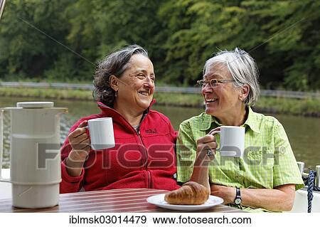 "Two holidaymakers having breakfast at the rear terrace of a Penichette, a houseboat on the Canal des Vosges, formerly Canal de l'Est, at PK 101, Girancourt, Epinal, Lorraine, Departement Vosges, France, Europe" View Large Photo Image Stock Photo - "Two holidaymakers having breakfast at the rear terrace of a Penichette, a houseboat on the Canal des Vosges, formerly Canal de l'Est, at PK 101, Girancourt, Epinal, Lorraine, Departement Vosges, France, Europe". Fotosearch
