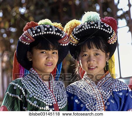 Stock Photo - "Two Lisu girls wearing colourful headdresses and the traditional costume of the mountain people, Mae Sai, Chiang Rai Province, Northern Thailand, Thailand, Asia". Fotosearch